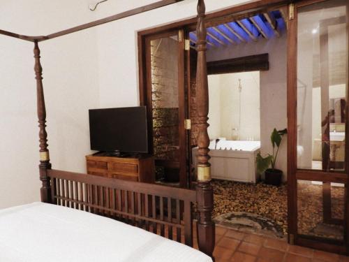 a bedroom with a bed and a tv and a mirror at Artisan Villa in Colombo
