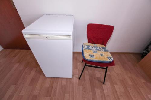 Apartments Adna في بوداكا: كرسي احمر جالس بجانب ثلاجة بيضاء
