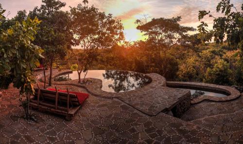 a patio with a bench and a pond and trees at Utopia Rote Lodge in Nembrala