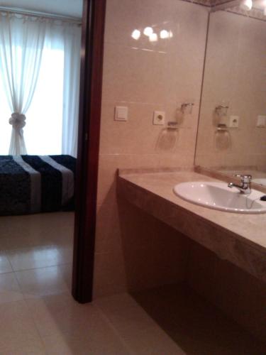 a bathroom with a sink and a mirror and a bed at Playa y Sol in Cubelles