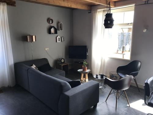 カラントスウオーフにあるQuaint Apartment in Callantsoog with Terraceのリビングルーム(青いソファ、椅子付)