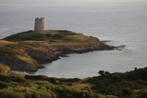 a lighthouse on a small island in the ocean at La Casa sulla collina "Baccu e Idda" in Chia
