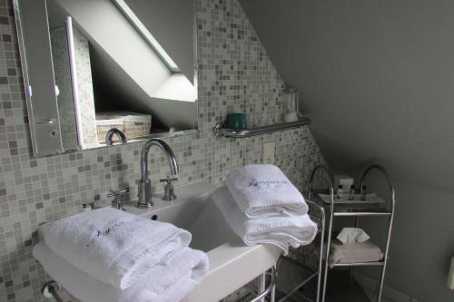 a bathroom with a sink with towels and a mirror at L'Agapanthe in Pléneuf-Val-André