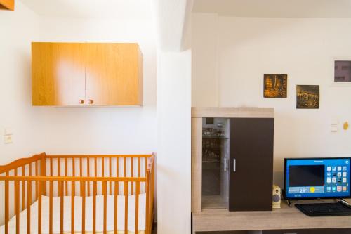 a room with a crib and a computer on a desk at Aris Palace in Elia