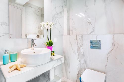 a white bathroom with a sink and a toilet at Asterias Premium Holiday Apartments in Pefkohori