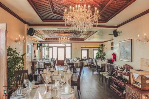 a dining room with tables and chairs and a chandelier at KERCULLA Resort in Gjirokastër