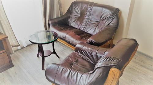 a living room with a leather couch and a glass table at Хотел "АВЕНЮ" in Stara Zagora