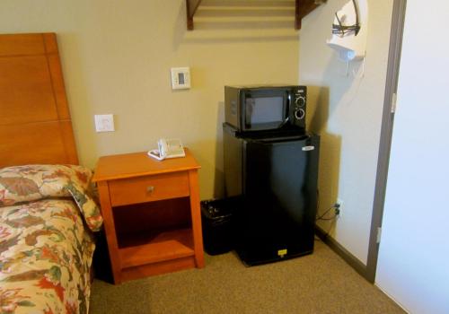 a room with a refrigerator and a tv and a bed at Deluxe Inn Redwood City in Redwood City