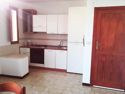 una cucina con armadietti bianchi e una porta rossa di La Praia 12 a Favignana