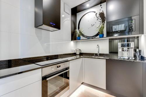 a kitchen with white cabinets and a sink at INA Rent - Tre Mare Apartamenty in Gdańsk