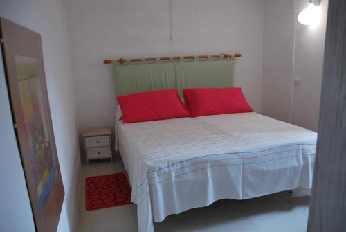 - une petite chambre avec un lit et des oreillers rouges dans l'établissement casa della notara, à Alezio