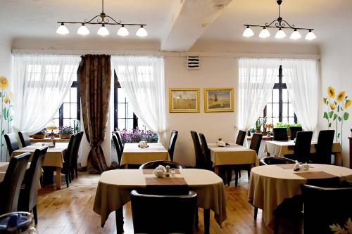 a dining room with tables and chairs and windows at Hotel Pod Orłem in Toruń