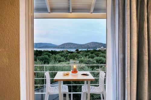 a table with a candle on a balcony with a view at Elounda Krini Hotel in Elounda