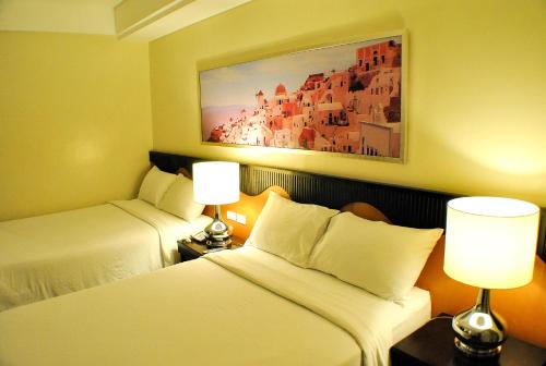a hotel room with two beds and two lamps at Hotel Elizabeth Cebu in Cebu City