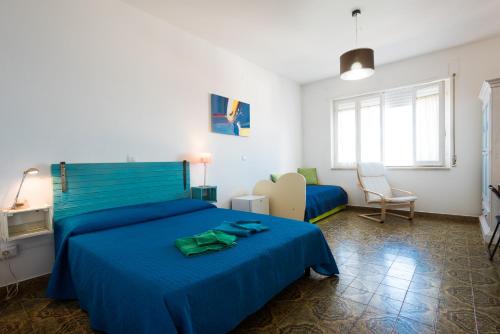 een slaapkamer met 2 bedden met blauwe lakens en een stoel bij B&B BentueMari in Portoscuso