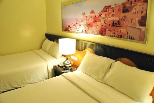 a hotel room with two beds and a painting on the wall at Hotel Elizabeth Cebu in Cebu City