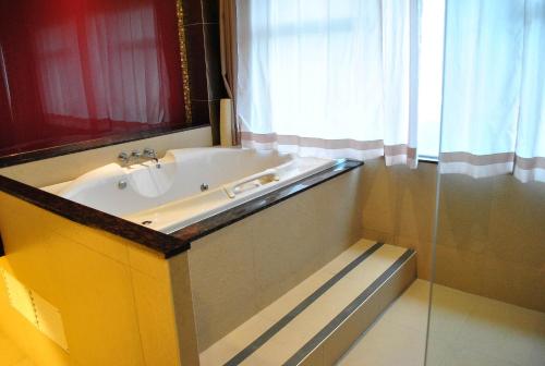 a bathroom with a tub and a sink and a window at Hotel Elizabeth Cebu in Cebu City