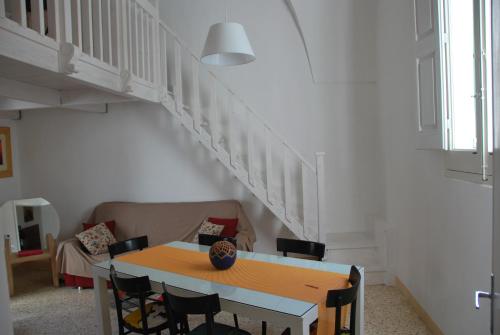 - une table et des chaises dans le salon avec un escalier dans l'établissement casa della notara, à Alezio