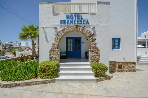 a white building with a blue door and stairs at Hotel Francesca in Agios Prokopios