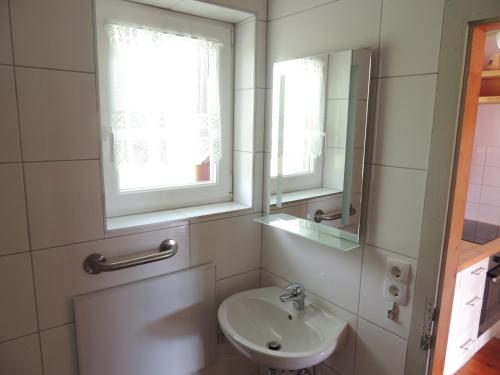 Baño blanco con lavabo y espejo en Ferienhäuser Zak, en Sankt Kanzian