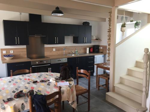 une cuisine avec une table et une cuisine avec des armoires noires dans l'établissement Maison de charme kertugal, à Saint-Quay-Portrieux