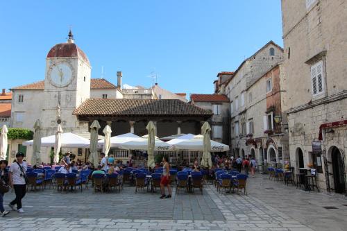 a group of people sitting at tables in a pavilion with a clock tower at Narancin Apartments in Trogir