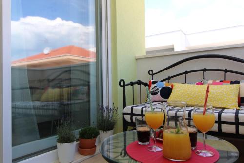 a balcony with a table with two glasses of juice at Narancin Apartments in Trogir