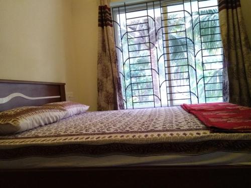 a bedroom with a bed with a window and a bedspread at Aikya in Mangalore