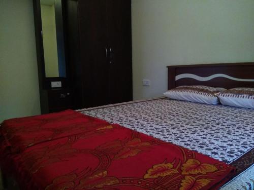 a bedroom with a bed with a red blanket on it at Aikya in Mangalore
