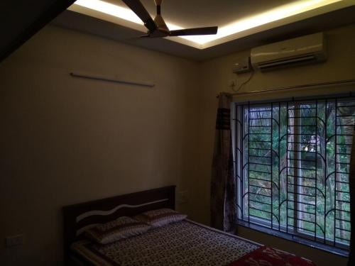 a bedroom with a ceiling fan and a window at Aikya in Mangalore