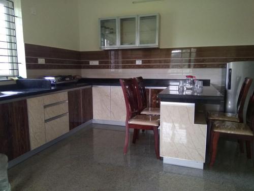 a kitchen with a table and chairs and a refrigerator at Aikya in Mangalore