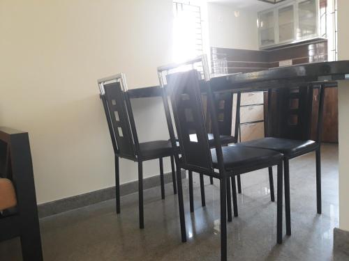 a dining room with black chairs and a table at Aikya in Mangalore