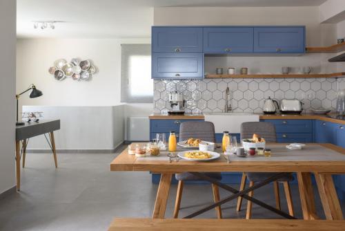 a kitchen with blue cabinets and a table with food on it at Ambeli Luxury Villa in Megalokhori