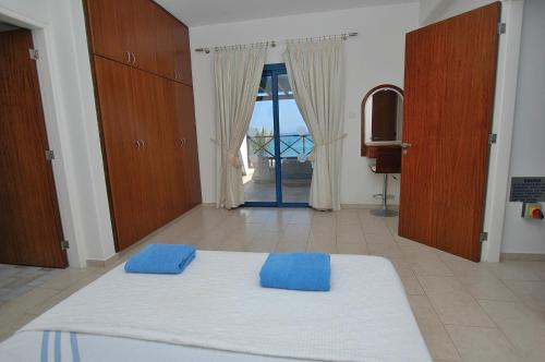 a bedroom with a bed with two blue pillows on it at Kymmates Beach Front Villas in Paphos City