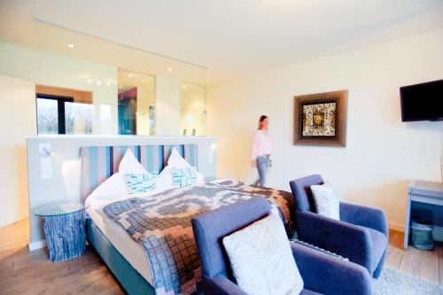 a bedroom with a bed and two blue chairs at Hotel Gut Bardenhagen in Bardenhagen
