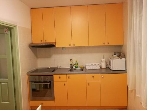 a kitchen with yellow cabinets and a sink at Apartman Paula in Biograd na Moru