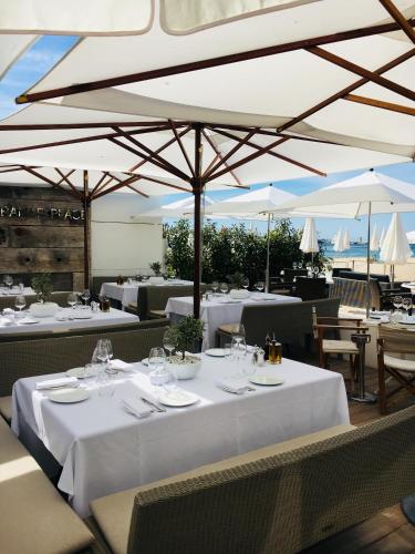 un restaurant avec des tables blanches et des parasols dans l'établissement Appartement Le Palais Des Iles, à Cannes