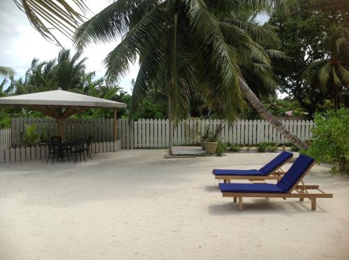 a blue lounge chair and an umbrella on the beach at Seashell Beach Villa in Grand'Anse Praslin