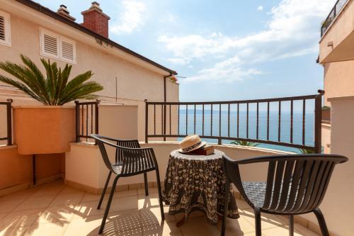 a balcony with two chairs and a table with a hat at Waterfront Roko in Podgora