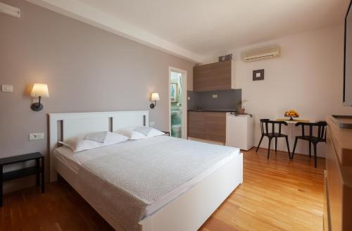 a bedroom with a white bed and a kitchen at Waterfront Roko in Podgora