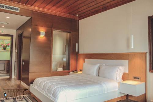 a bedroom with a white bed with a wooden headboard at KERCULLA Resort in Gjirokastër