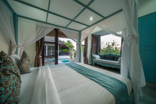 een slaapkamer met een hemelbed en een bank bij Villa Michiko in Uluwatu