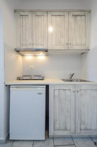 a kitchen with white cabinets and a sink and a refrigerator at Hotel Francesca in Agios Prokopios