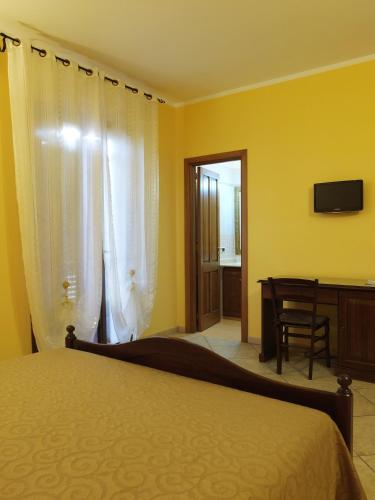a bedroom with a bed and a desk and a television at Villa Musica in Sannicola