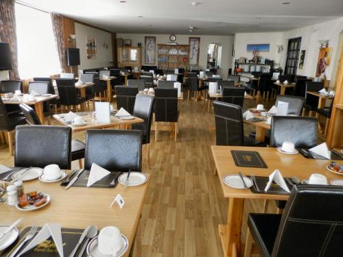 uma sala de jantar com mesas e cadeiras de madeira e tampo de mesa em Wayside Cheer Hotel em Castel