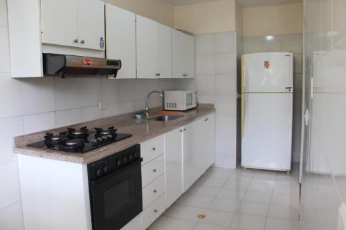 a kitchen with a stove and a white refrigerator at Casa Quinta Melgar in Melgar