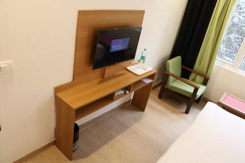 una habitación con un escritorio con televisión y una silla en The Three Oaks Boutique Hotel, en Mussoorie