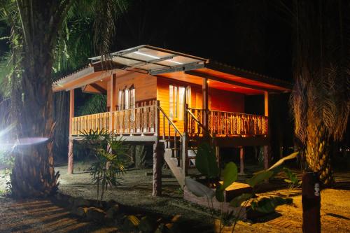a small wooden house with a balcony in the night at Khao Sok Palmview Resort in Khao Sok