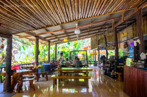 a restaurant with wooden tables and people sitting in it at Khao Sok Palmview Resort in Khao Sok