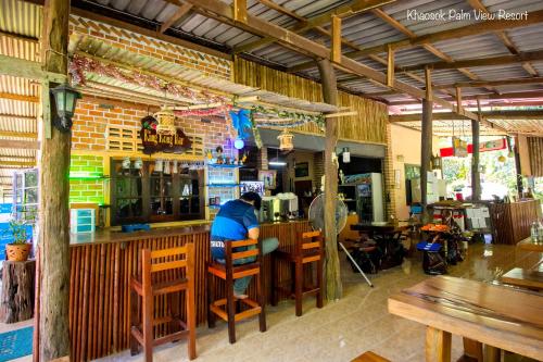 a man sitting at a bar in a restaurant at Khao Sok Palmview Resort in Khao Sok